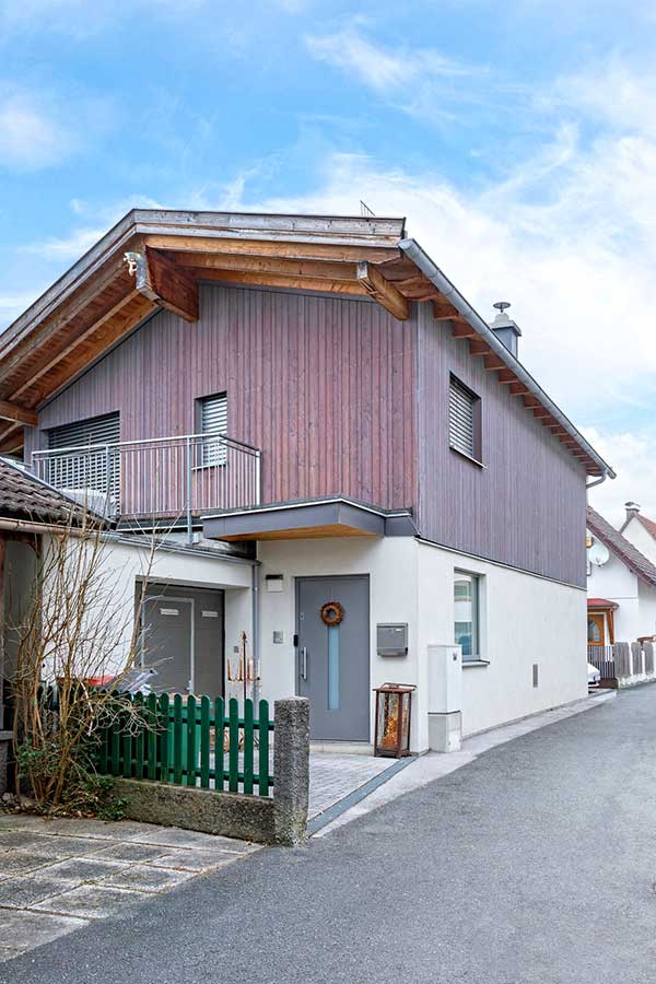 Zweistöckiges Haus mit holzverkleidetem Obergeschoss und kleinem Balkon über dem Eingang © SARA BUBNA photography